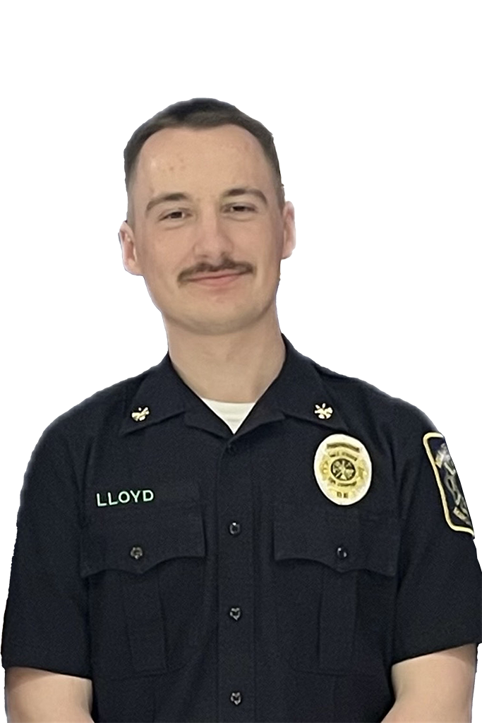 A person in a dark uniform with badges and the name "Lloyd" on it is smiling. They have short hair and a mustache. The background is a light grey.